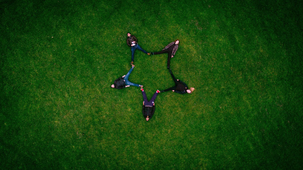 people in the grass sitting in a form of a star